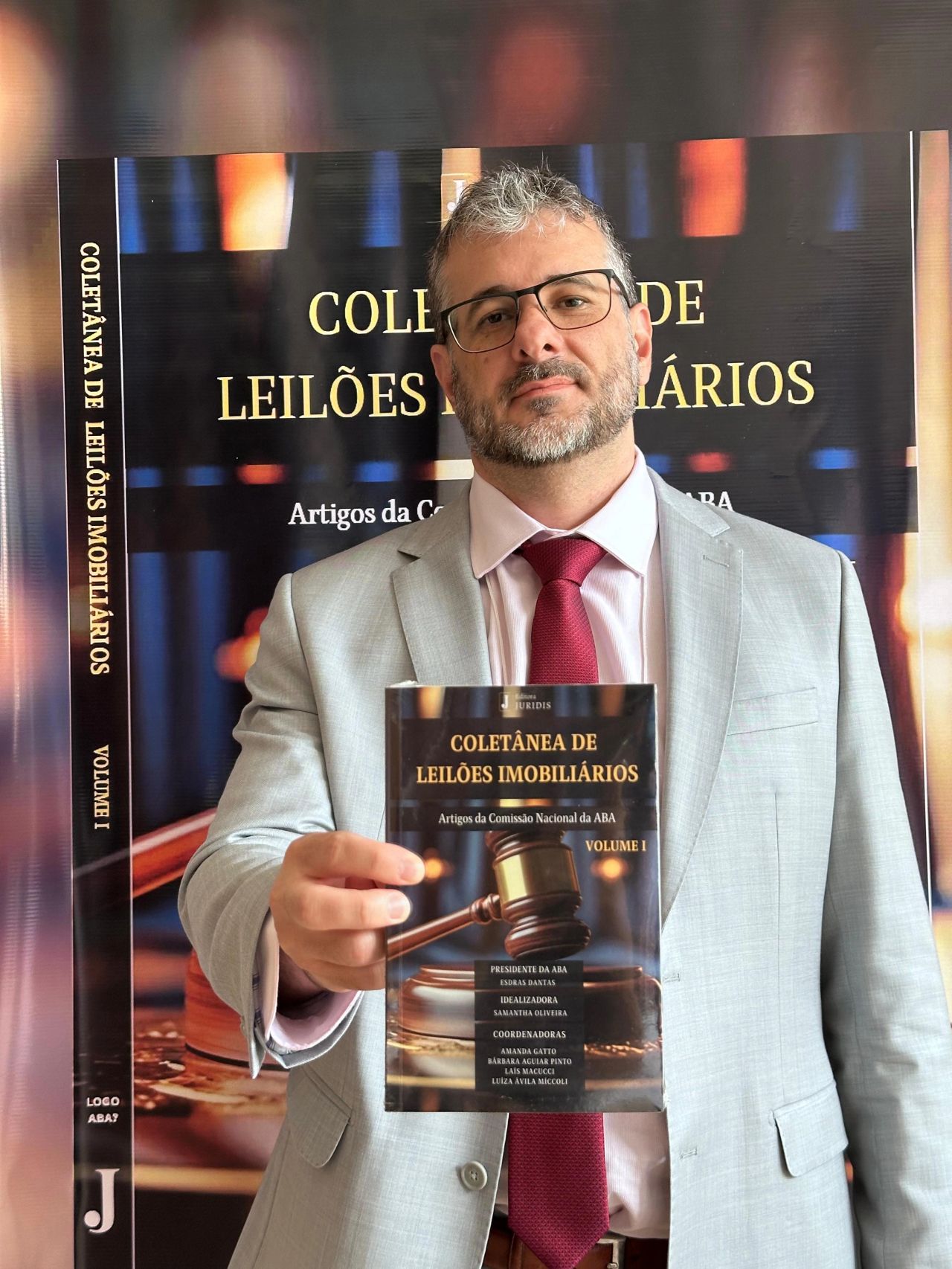Prof. Dr. Aurélio Viana segurando o livro Coletânea de Leilões Imobiliários